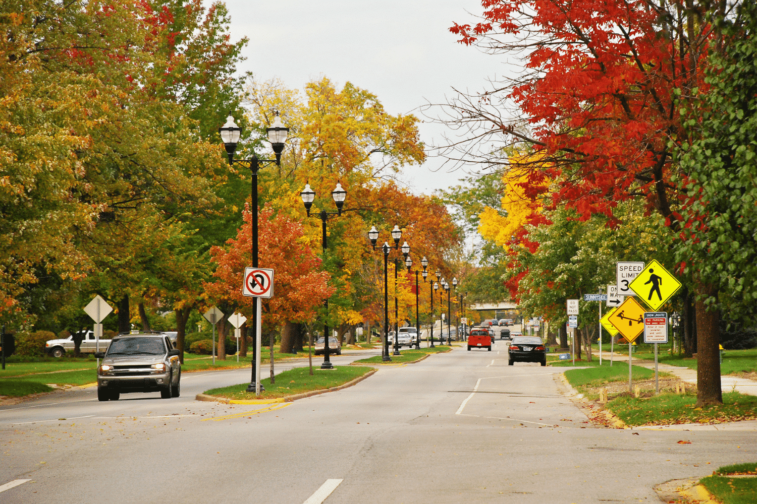 midwest neighborhood street in autumn with cars and street signs